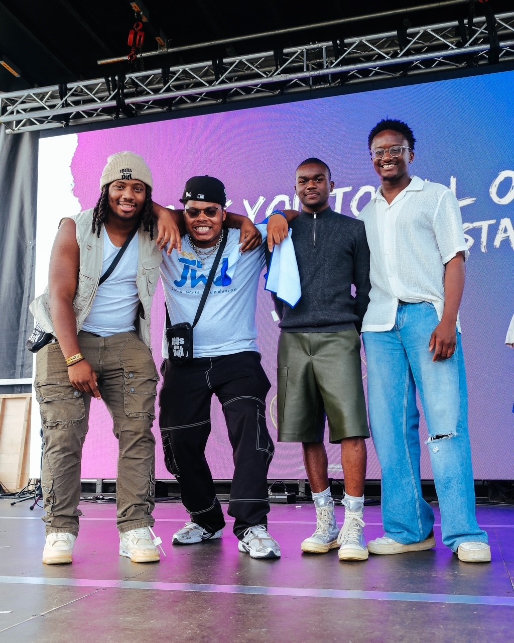 Four young men stand together on stage, smiling after winning 1st, 2nd & 3rd place for 2025 T.I.P (Teens in the Parks) Fest.